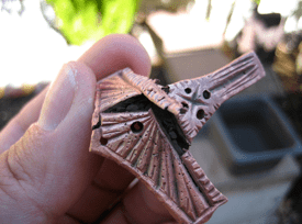 Hand holding a broken clay object piece.