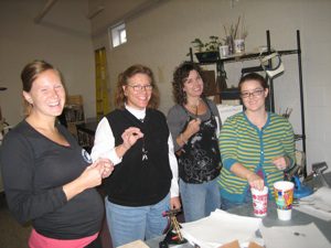 Four women smiling in a casual setting.
