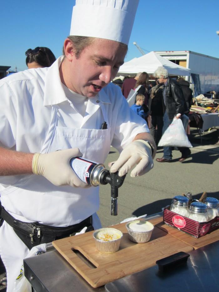 Chef using blowtorch on desserts outdoors.