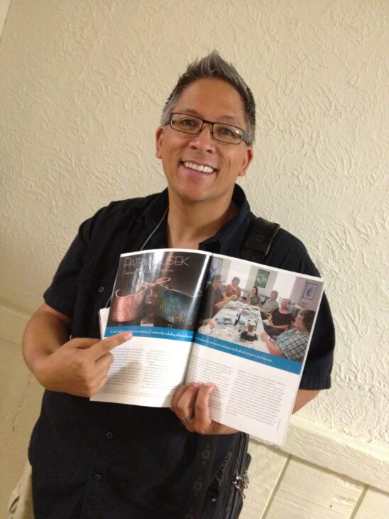 Person smiling and holding an open magazine.
