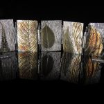Metallic leaf designs on reflective surface.
