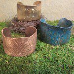 Three textured metal cuff bracelets displayed outdoors.