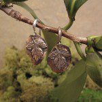 Leaf-shaped earrings hanging on a branch.