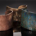 Three textured metal cuff bracelets displayed.
