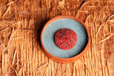 Red button in round wooden container.