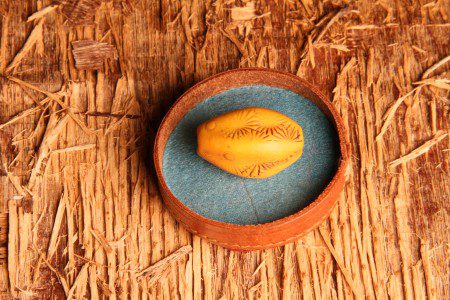 Yellow seed in a round wooden container.