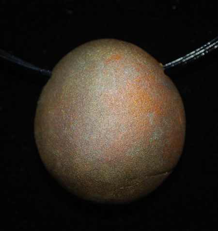 Rusty, round object against a dark background.