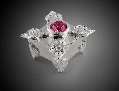 Ornate silver box with pink gemstone lid.