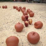 Clay sculptures resembling apples on sandy ground.