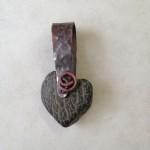 Heart-shaped stone pendant with metal loop.