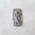 Rectangular carved silver pendant on display.