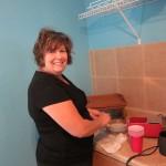 Woman smiling while washing dishes in kitchen.