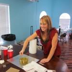 Woman stirring mixture at craft workshop table.