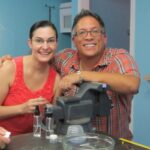 Two people smiling beside a microscope.