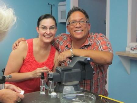 Two people smiling beside a microscope.