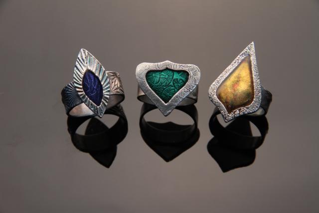 Three artistic rings on a reflective surface.