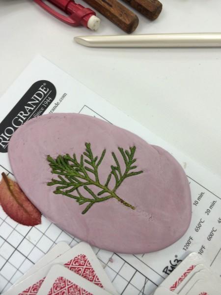 Pink clay with pressed green leaf imprint.