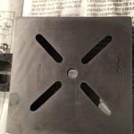 Metal plate with four diagonal slots.