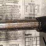 Metal rod on newspaper with text background.