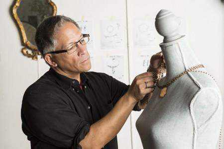 Man adjusting necklace on a dress form.