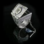 Silver ring with eye design, black background.
