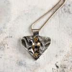 Heart-shaped silver pendant with amber stones.