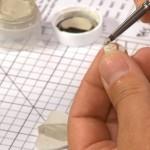 Hand painting a small object with brush.