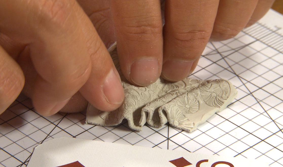 Hands folding patterned fabric on grid paper.