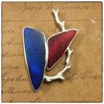 Blue and red abstract brooch on paper.