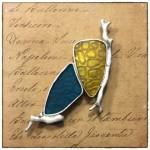 Colorful stained glass brooch on handwritten paper.