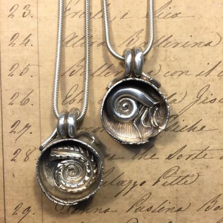 Silver spiral pendants on handwritten background.