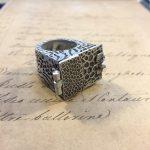 Intricate silver ring on handwritten paper.