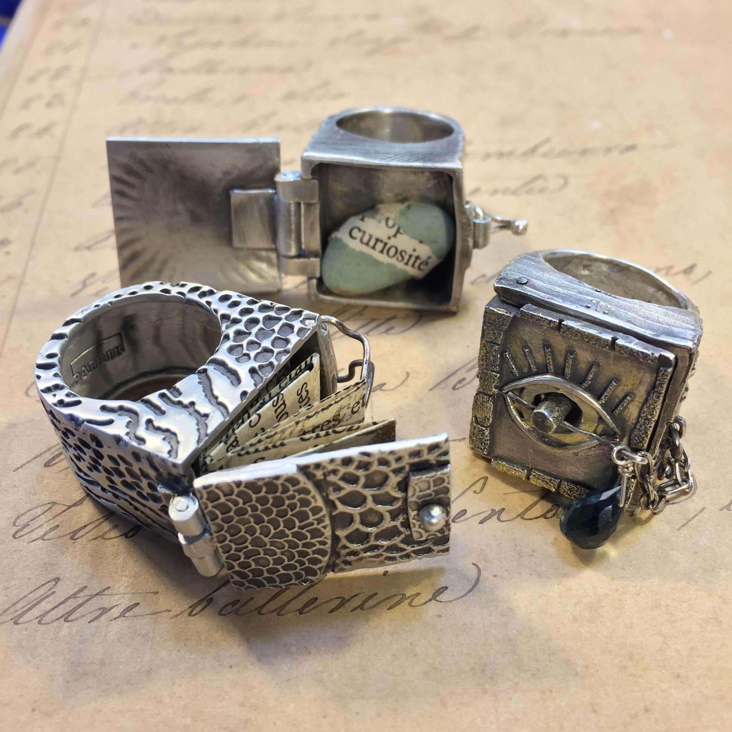 Silver rings with intricate designs and compartments.