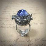 Silver ring with blue gemstone on paper.
