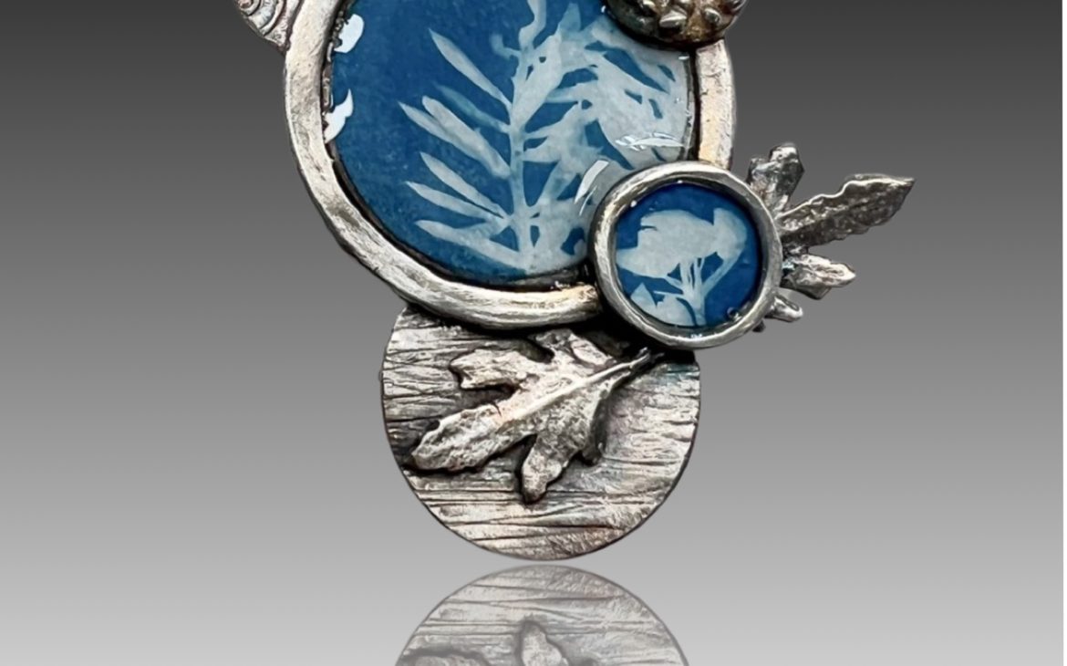 Artistic brooch with blue leaf design.