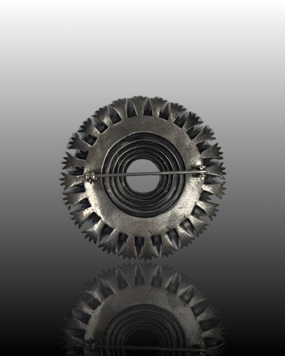 Metallic circular object with jagged edge design.